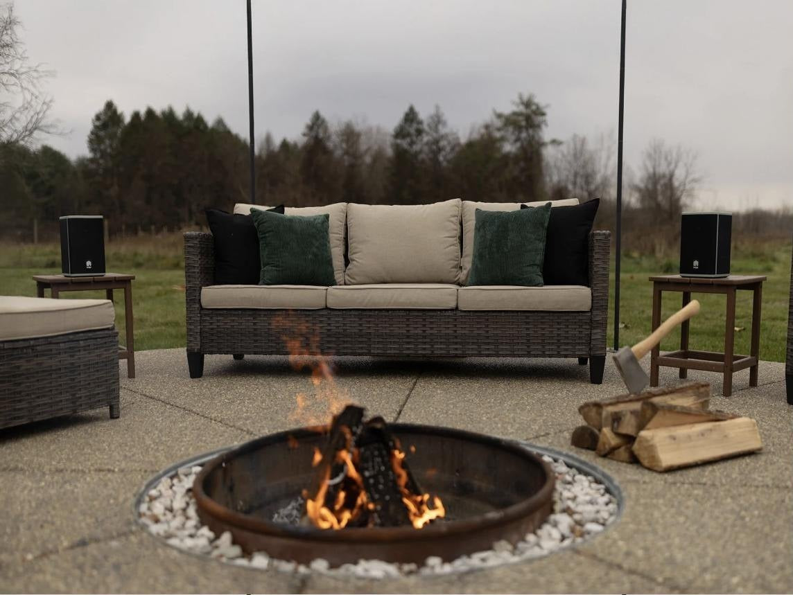 Two Lodge Solar Speakers beside an outdoor fire pit