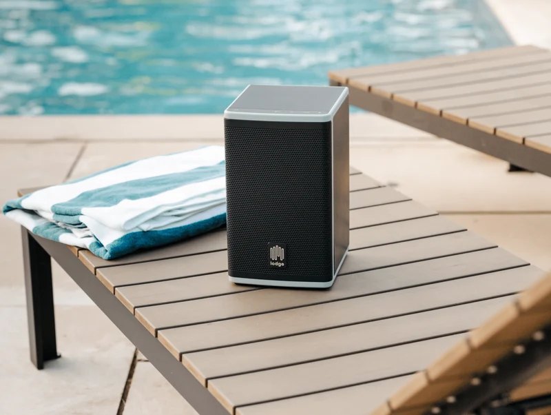 A Lodge Solar Speaker 4 on a poolside lounge table